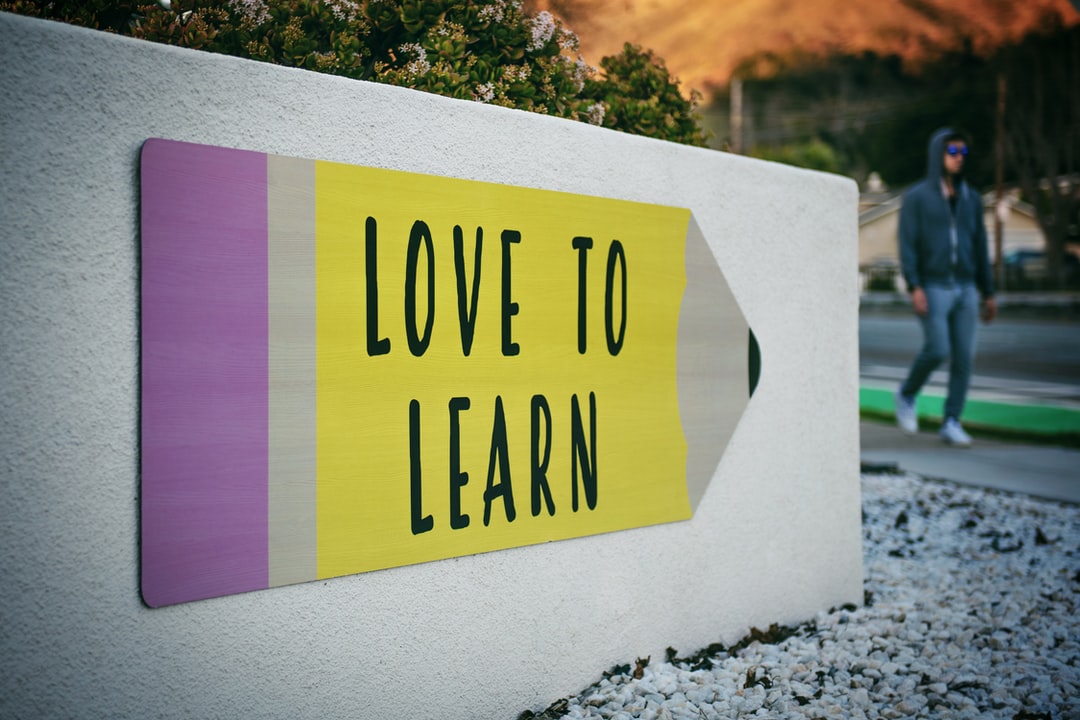 love to learn pencil signage on wall near walking man love to learn pencil signage on wall near walking man